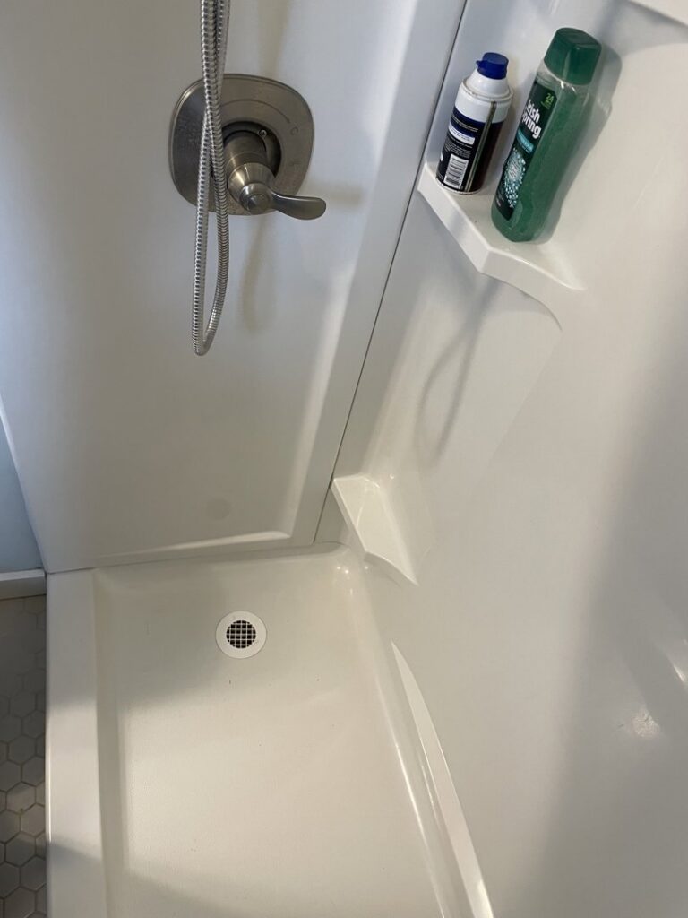 A spotless shower interior with a clean shower head and organized bottles, cleaned by Maid In Indy in Indianapolis, IN.