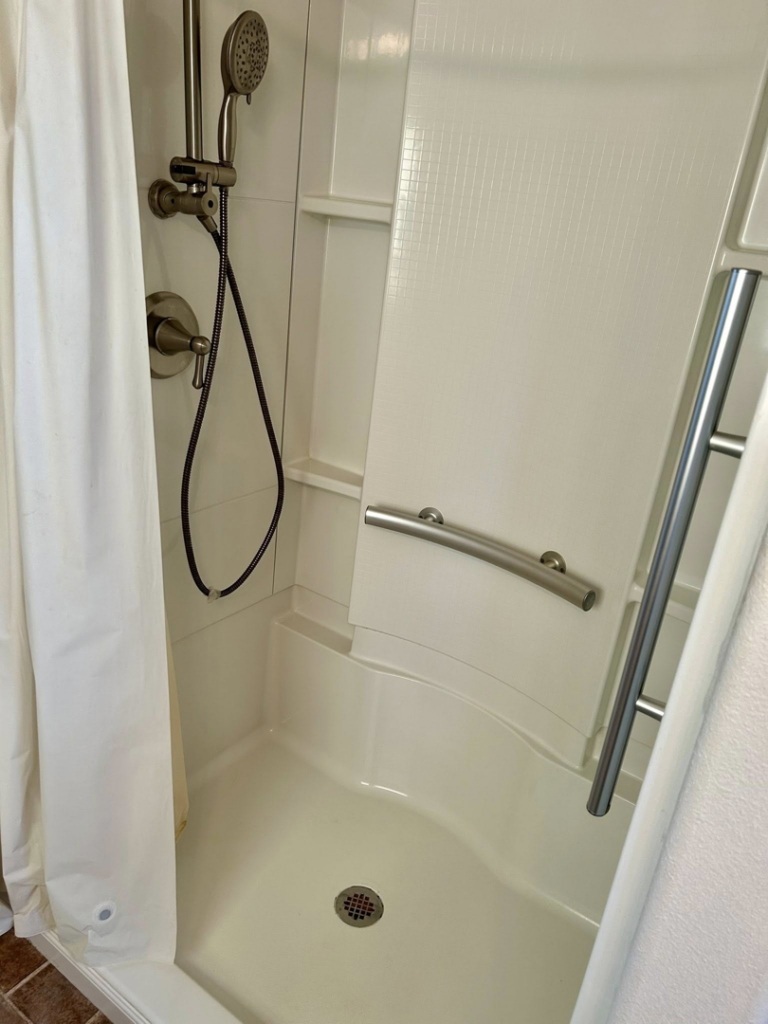 A spotless and clean shower stall with a shower head and grab bars, demonstrating the bathroom cleaning expertise of Elite A&C Cleaning, LLC in Casper, WY.