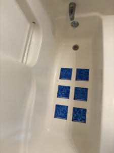 A spotless white bathtub with blue accent tiles after professional cleaning by Warm & Cozy House Cleaning in Madison, WI