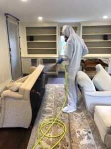A Green Home Solutions technician spraying a dresser for mold treatment or disinfection after water damage in Mount Airy, MD.