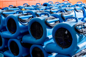 A large stack of blue air movers, essential drying equipment used by Flood Pros for water damage restoration in Sandy, UT.