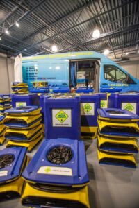 Stacks of air movers and dehumidifiers with company branding, ready for deployment by 1-800 WATER DAMAGE of Oklahoma City, OK.