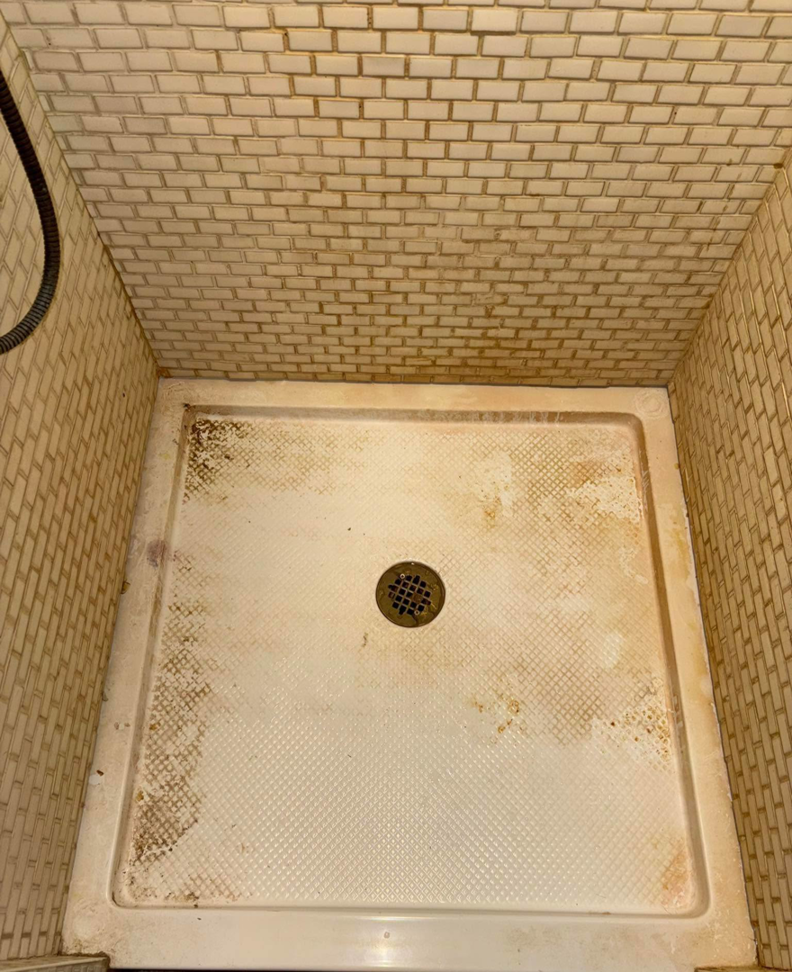 A stained and dirty shower floor before professional cleaning by Carissa's Green Cleaning LLC in Toledo, OH.