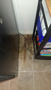 A stained and dirty floor area behind furniture before a thorough cleaning by Quality Cleaning for Less in Los Angeles, CA.