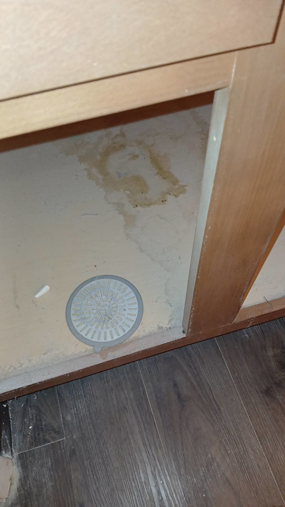 A stained and dusty floor area under a cabinet, highlighting a challenging cleaning task for On Point Cleaning Authority in Dayton, OH.