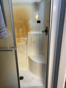 A stained shower stall with rust and grime before cleaning by Crystal's Small Town Cleaning Company, LLC in Oelwein, IA.