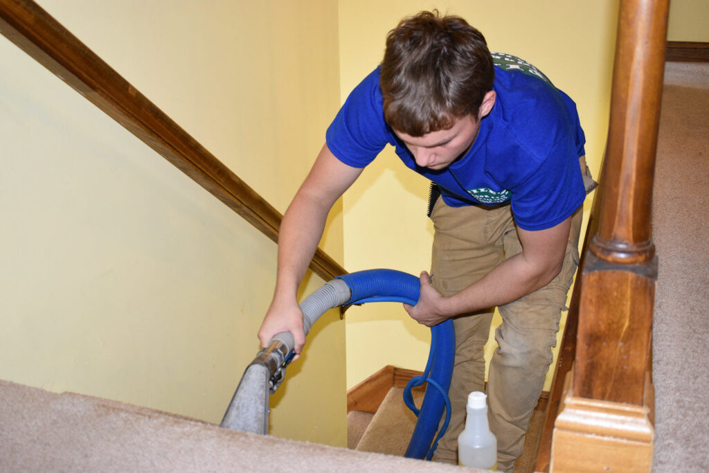 A technician from Pile's Carpet Care & Restoration Service cleaning carpet on a staircase in Elizabethtown, KY.