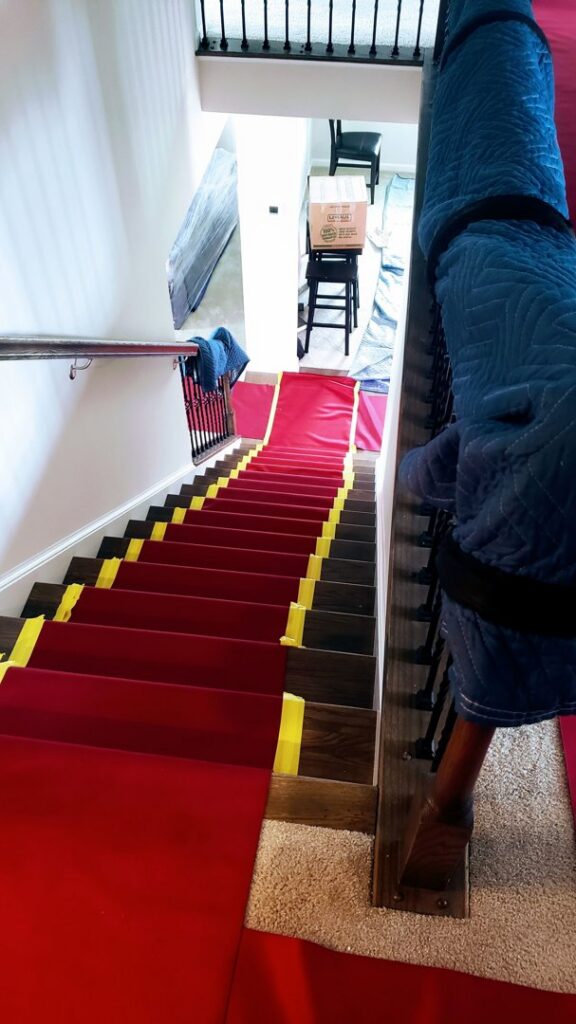 A staircase protected with red runners and moving blankets, prepared by S&P Network's Marathon Moving Solutions in Mechanicsburg, PA.