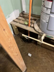 Standing water on the floor around a water heater, indicating water damage remediation by Hull Plumbing, Inc. in Oklahoma City, OK.