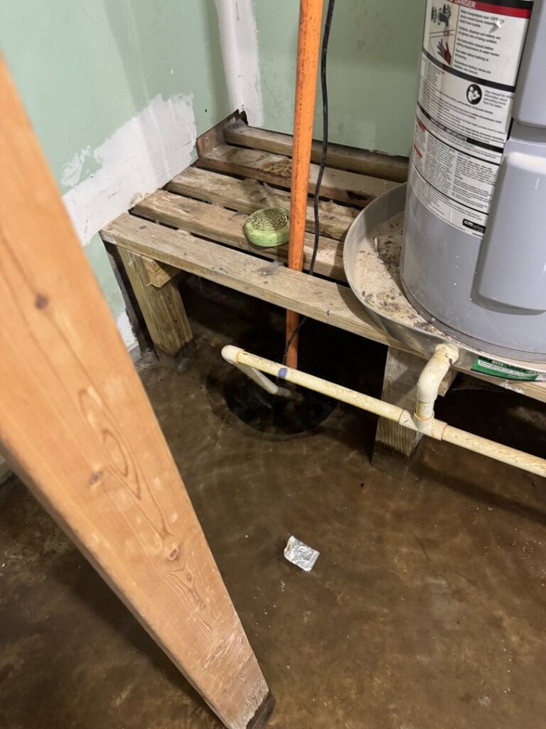 Standing water on the floor around a water heater, indicating water damage remediation by Hull Plumbing, Inc. in Oklahoma City, OK.