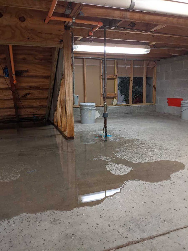 Standing water on a concrete floor in a basement, indicating severe water damage in Northport, AL.
