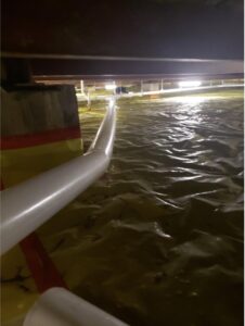 Standing water in a crawl space with a pump hose visible, indicating water extraction by SO-CO Water Damage in Pueblo, CO.