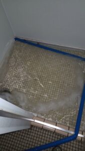 A tiled floor with standing water contained by blue barriers, showing water damage by North Shore Restore in Duluth, MN