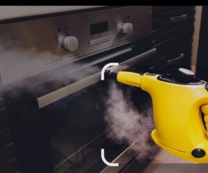 A yellow handheld steam cleaner being used to clean the inside of an oven by D A E S Cleaning LLC in Billings, MT.
