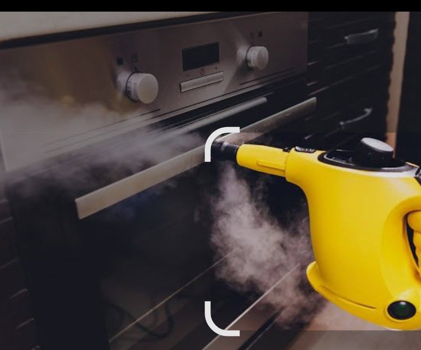 A yellow handheld steam cleaner being used to clean the inside of an oven by D A E S Cleaning LLC in Billings, MT.