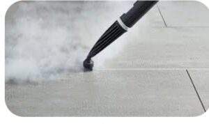 A close-up of a steam cleaner nozzle cleaning a tiled floor, emitting steam, by D A E S Cleaning LLC in Billings, MT.