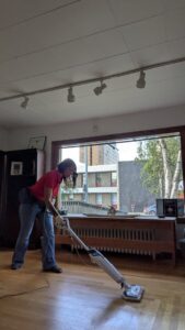 A professional cleaner from Leave The Dust To Me Cleaning Services LLC in Anchorage, AK, steam mopping a wooden floor.
