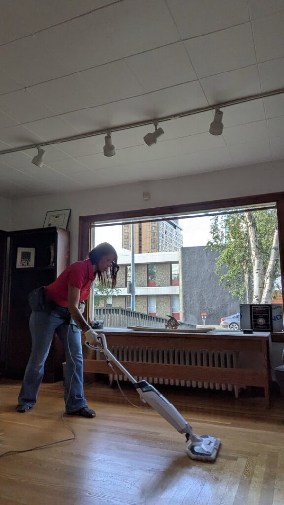 A professional cleaner from Leave The Dust To Me Cleaning Services LLC in Anchorage, AK, steam mopping a wooden floor.