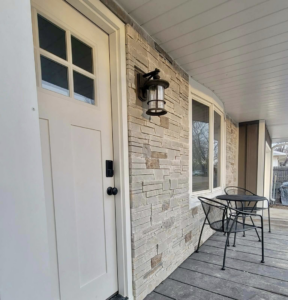Close-up of a house entrance featuring stone veneer and vertical siding installed by D.A. Siding & Windows in Grand Island, NE.