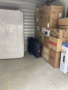 A storage unit neatly packed with moving boxes and a wrapped mattress, handled by Houston Affordable Movers in Houston, TX.
