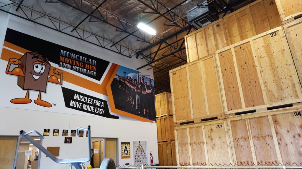 Interior view of a storage warehouse with tall stacks of wooden crates at Muscular Moving Men & Storage in Phoenix, AZ.