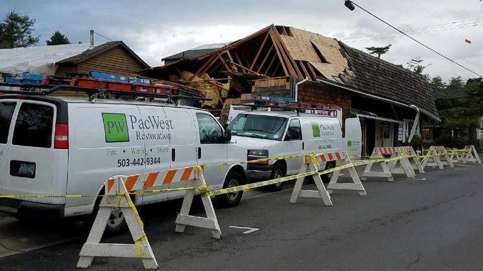 PacWest Restoration vans at a storm-damaged building, ready for restoration services in Tigard, OR