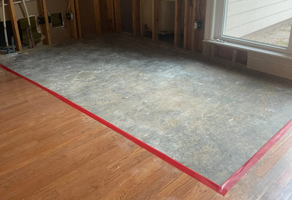 Stripped subfloor with red tape, indicating an area undergoing water damage remediation by 1st Response Emergency Repairs, LLC in Scott, LA.