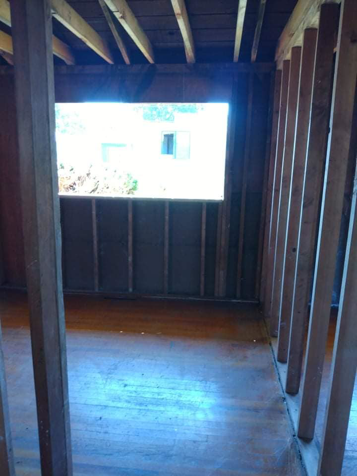 Stripped room interior with exposed studs and a large window, part of a demolition project by Building Assisting Group Demolition INC in Tacoma, WA.