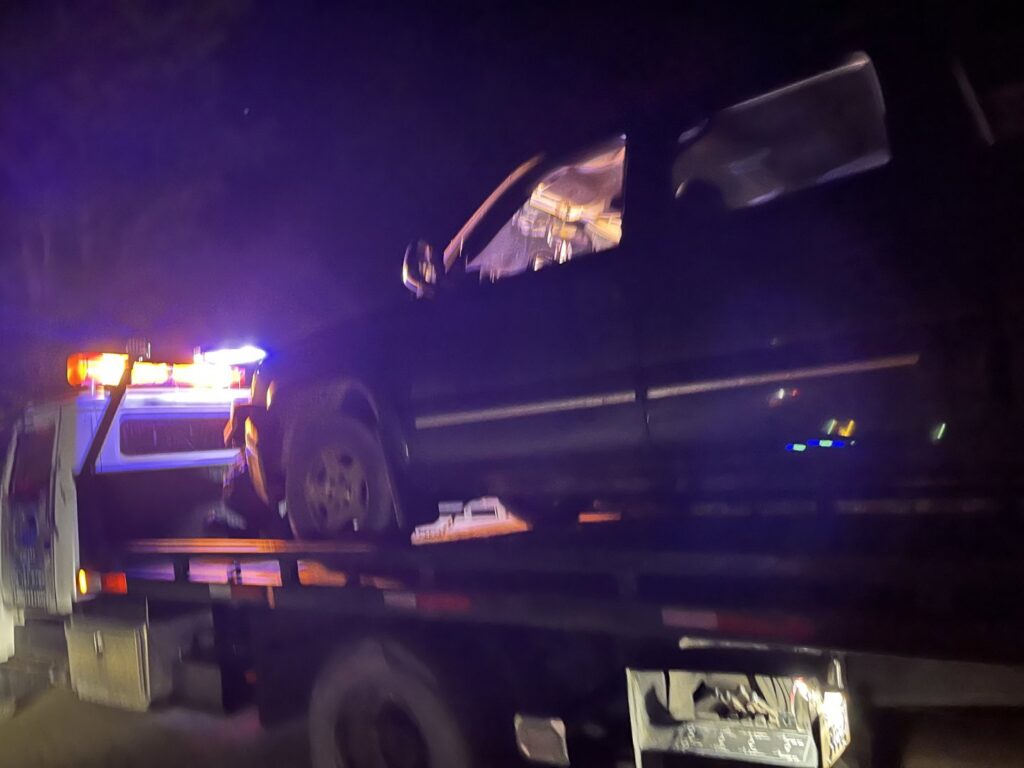 A dark SUV being loaded onto a flatbed tow truck at night by TNF Towing in Montrose, PA.