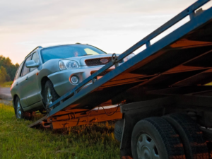 A silver SUV being loaded onto a flatbed tow truck at dusk by On Time Towing Houston, TX.