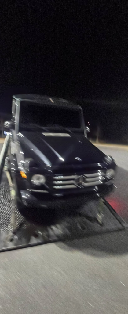A dark SUV being carefully loaded onto a flatbed tow truck by Dees Custom Auto in Newnan, GA.