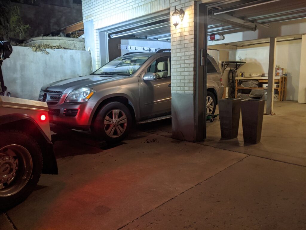 A grey SUV being towed out of a garage by a 4 Wheel Towing truck at night in South Salt Lake, UT.
