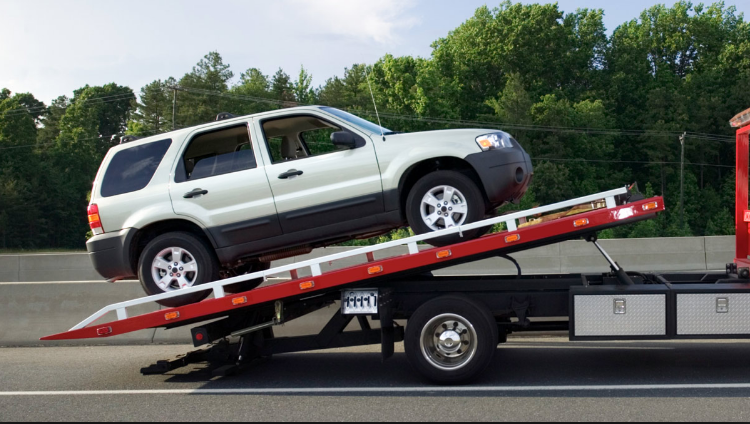 A white SUV being loaded onto a red flatbed tow truck by Alexandria VA Towing in Alexandria, VA.