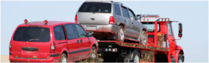 A silver SUV being transported on a red flatbed tow truck by On Time Towing Houston, TX.