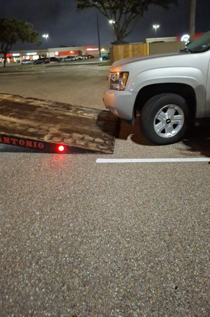 A silver SUV parked next to a flatbed tow truck from CC Wrecker Service, ready for towing in Corpus Christi, TX.
