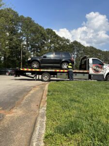A flatbed tow truck from Raleigh Towing & Recovery loading a black SUV in Raleigh, NC.