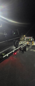 A dark SUV fully loaded and secured on a flatbed tow truck from Dees Custom Auto in Newnan, GA.