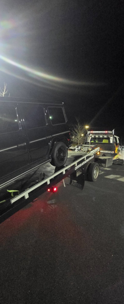 A dark SUV fully loaded and secured on a flatbed tow truck from Dees Custom Auto in Newnan, GA.