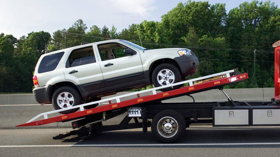 An SUV being loaded onto a flatbed tow truck on a highway by St Pete Towing Services in Saint Petersburg, FL.