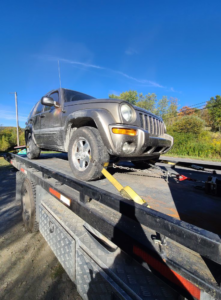 A dark SUV secured on a flatbed tow truck, ready for transport by TNF Towing in Montrose, PA.