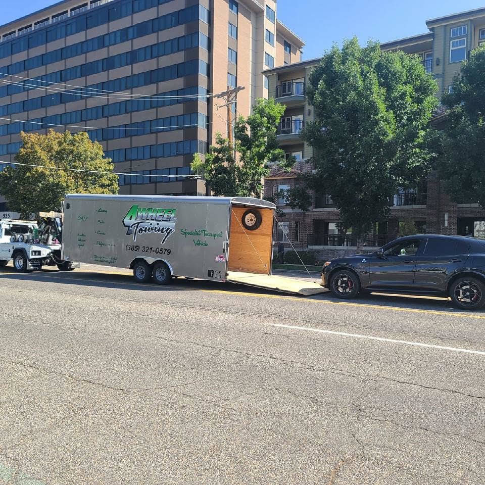 A 4 Wheel Towing truck assisting with a black SUV towing an enclosed trailer in South Salt Lake, UT.