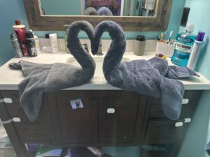 Two towels artfully folded into swan shapes on a clean bathroom vanity by Nichole's Cleaning Service in Fort Wayne, IN