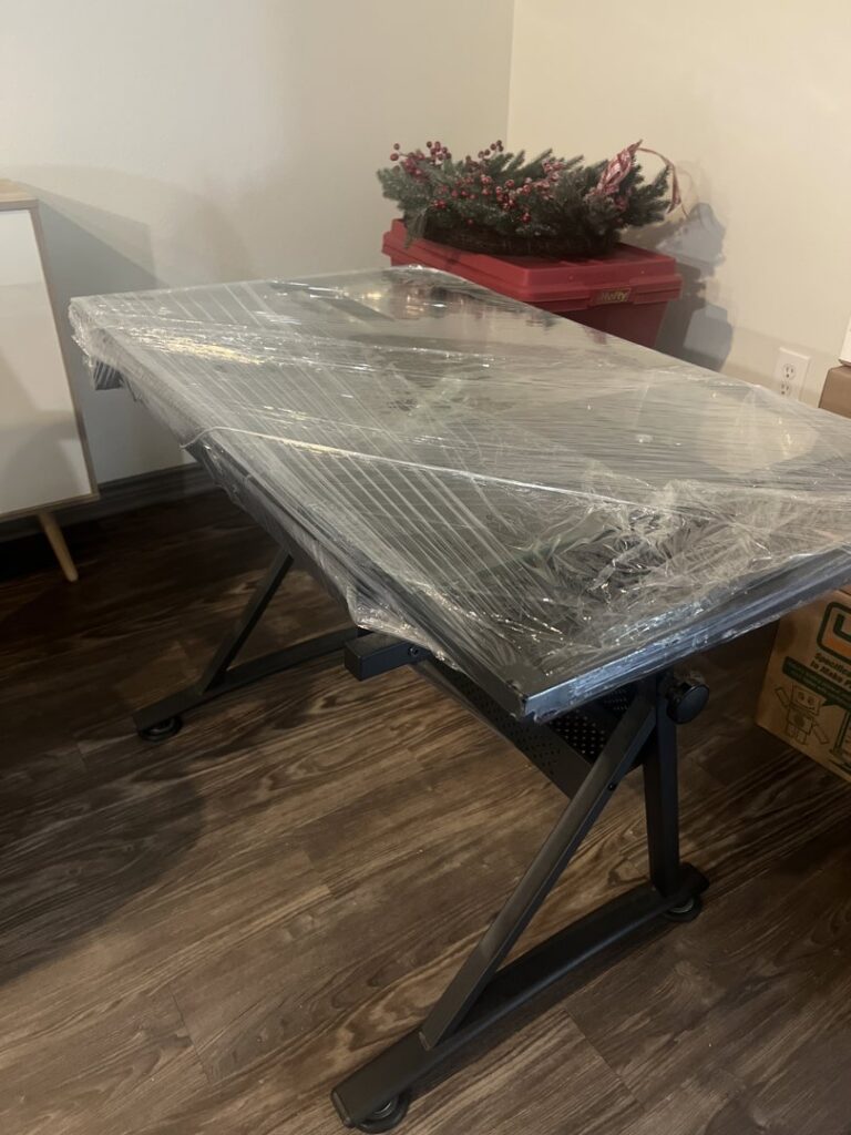 A table meticulously wrapped in plastic for protection during transit, prepared by Houston Affordable Movers in Houston, TX.