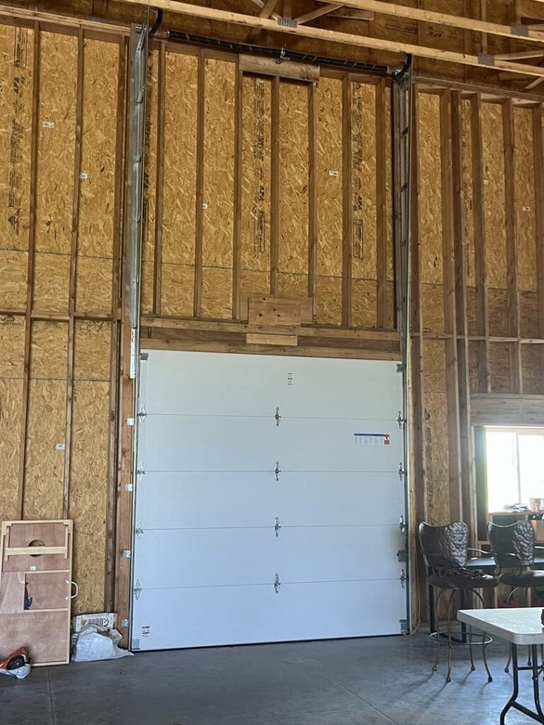 Interior view of a tall garage door installation in a commercial building by Over The Top Garage in Albuquerque, NM.