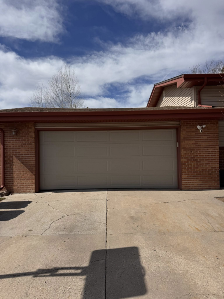 A tan paneled residential garage door installed by Cowboy State Garage Doors, LLC in Cheyenne, WY.