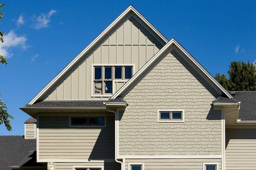 A house featuring tan horizontal siding and decorative shingle siding on the gable by HP Exteriors in Woodstock, GA