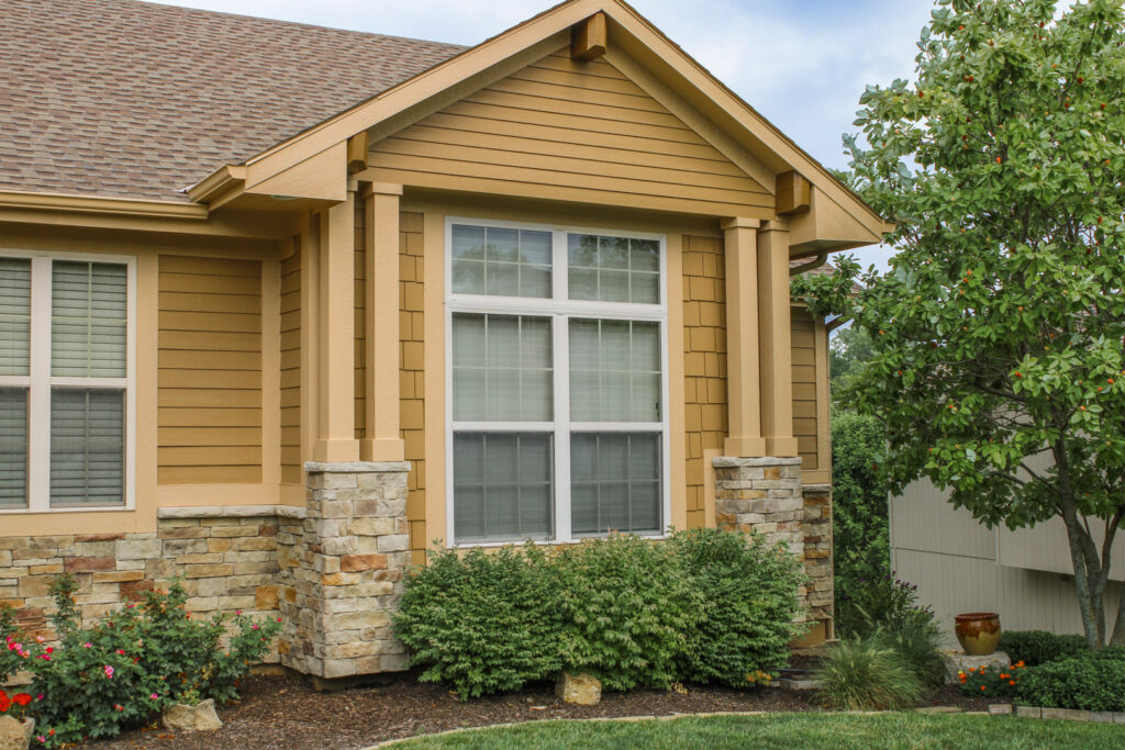 A residential home with attractive tan horizontal siding and decorative stone columns by Xtreme Exteriors in Rogers, AR.