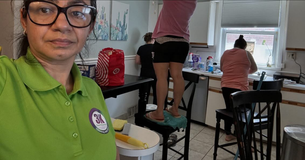 A team from 3K Cleaning Service diligently cleaning a kitchen in Philadelphia, PA, with one cleaner on a chair reaching high.