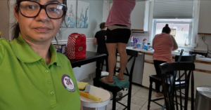 A team from 3K Cleaning Service diligently cleaning a kitchen in Philadelphia, PA, with one cleaner on a chair reaching high.