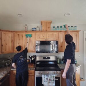 Two members of the E-N-S Home Cleaning Solutions, LLC team cleaning kitchen cabinets in a home in Lewiston, ID.